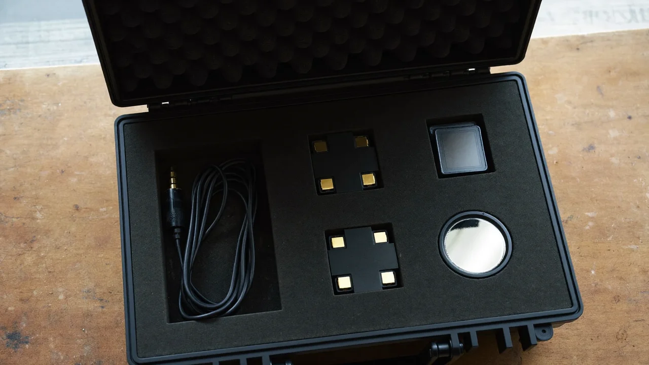 Geöffneter Hartschalenkoffer mit Kabeln, Akkus, Kartenboxen und kleinem Reflektor von oben