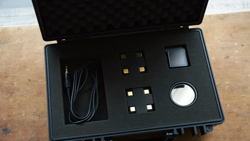 Geöffneter Hartschalenkoffer mit Kabeln, Akkus, Kartenboxen und kleinem Reflektor von oben